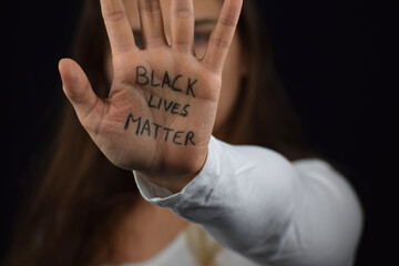 White woman's palm with Black Lives Matter slogan written on her palm. Young Caucasian solidarity...
