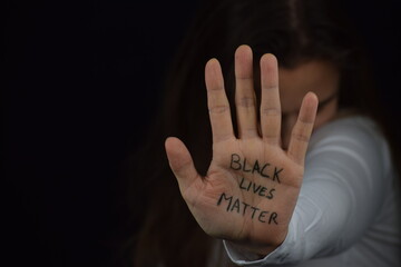 White woman's palm with Black Lives Matter slogan written on her palm. Young Caucasian solidarity...