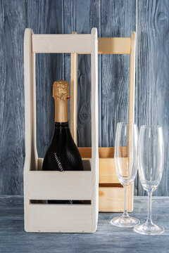 a bottle of champagne in a wooden box. next to 2 glasses of champagne. the holiday is March 8, mother's day.