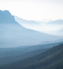 Obraz premium Hazy valley with mountains silhouettes, shot at Mount St. Piran summit, Banff National Park, Alberta, Canada
