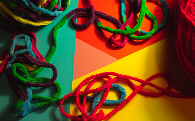 Hilo multicolor con hilo de lana de color rojo sobre unas cartulinas de distintos colores