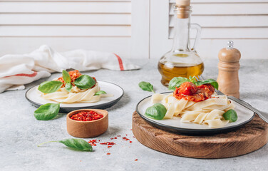 Pasta Tagliatelle Bolognese with meat tomato sauce and fresh basil leaves on white plate and wooden cutting board. Light gray table.