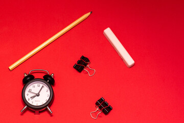 Stationery and alarm clock on a red background. Business Planning Concept. Place for text, copy space. The photo
