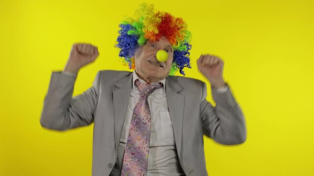 Elderly clown businessman entrepreneur boss dancing, entertains, celebrate