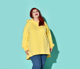 Plump red-haired woman in stylish casual attire posing calmly with beautiful smile. Three quarter length portrait isolated on blue, copy space