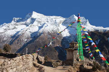 Panoramic view of Kangtega and Thamserku mountains and buddhist chorten with prayer flags on the...