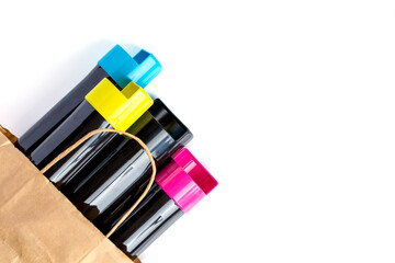 Set of cartridges for color laser printing lie on a table in a paper bag on a white background.