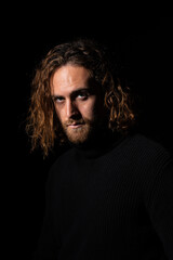 attractive man with long hair with blue eyes looking at camera on black background