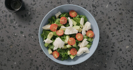 Top view salad with tomatoes , avocado, mozzarella and kale leaves in blue ceramic bowl on concrete background