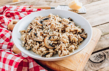 Homemade traditional Italian mushroom risotto on rustic wooden background. Classic Risotto with mushrooms served on a white plate