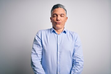 Middle age handsome grey-haired business man wearing elegant shirt over white background making fish face with lips, crazy and comical gesture. Funny expression.