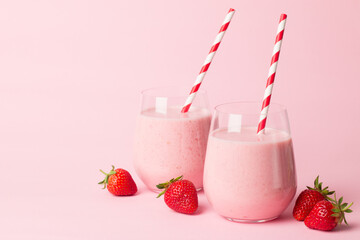 A glass of fresh strawberry smoothie on a pink background. Summer drink shake, milkshake and refreshment organic concept.