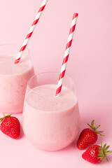 A glass of fresh strawberry smoothie on a pink background. Summer drink shake, milkshake and...