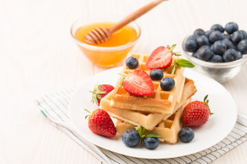 Photo of fresh homemade food made of Belgian waffles with honey, chocolate, strawberry, blueberry. Healthy dessert breakfast concept. 