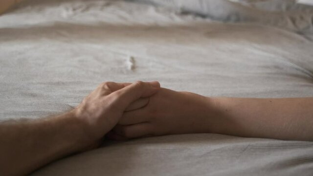 Close up of woman's hand touching bed sheets feeling sensual mans hand holding woman&rsquo;s hand



