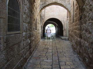 A woman enters an arch on a narrow street of an ancient city