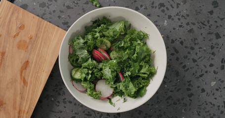 Top view mix salad from radish, cucumbers, kale salad and herbs with dressing