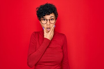 Fototapeta na wymiar Young beautiful african american afro woman wearing turtleneck sweater and glasses Looking fascinated with disbelief, surprise and amazed expression with hands on chin