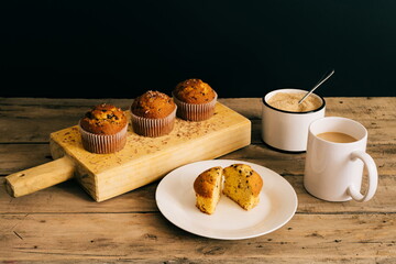 still life of muffins with chocolate shavings on wooden board accompanied by coffee and brown sugar