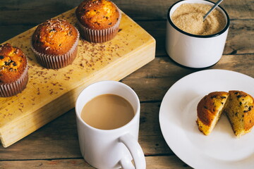 still life of muffins with chocolate shavings on wooden board accompanied by coffee and brown sugar