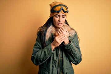 Young beautiful hispanic woman wearing ski glasses and coat for winter weather Suffering pain on hands and fingers, arthritis inflammation