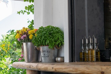 Flower metallic pots and glass jars of olive oil on a bench at a taverna