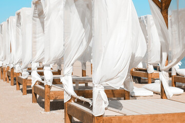 Fototapeta na wymiar Sun beds on the beach with a white veil. Family vacation concept. Beach beautification concept.