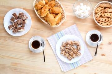 Cup of coffee on a napkin a wooden table and sweets with sugar.