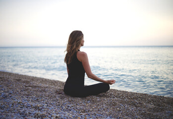 Fototapeta na wymiar woman doing yoga at sunset on the beach
