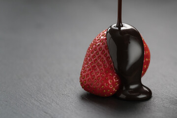 Pour chocolate over ripe strawberry on slate background