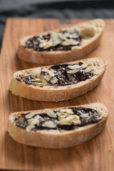 sweet breakfast ciabatta with chocolate hazelnut spread and almond flakes on wood board