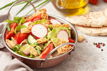 Traditional fattoush salad on a plate with pita croutons, cucumber, tomato,radish and herbs