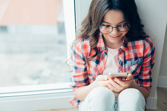 Contented teenager using modern smartphone and smiling