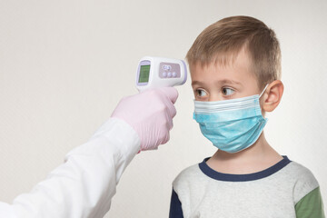Measuring the kid's temperature with a infrared thermometer