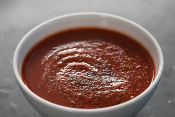 spicy tomato soup puree in white bowl on concrete background