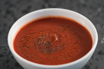 spicy tomato soup puree in white bowl on concrete background