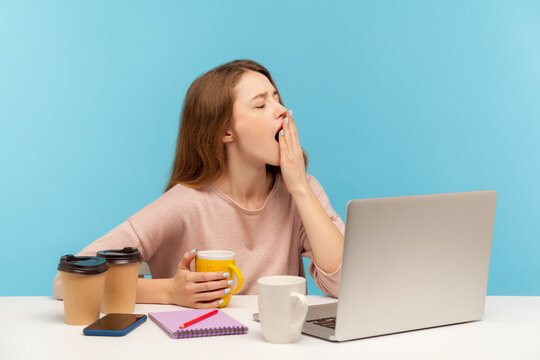 Exhausted woman, office employee surrounded by coffee cups in workplace, yawning, dreaming of sleep, feeling fatigued and stressed, overtime work. indoor studio shot isolated on blue background