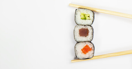 Japanese kitchen. Various sushi and rolls with fish cheese and with chuka salad in chopsticks