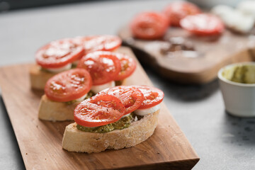 Bruschetta with tomatoes, mozzarella and pesto on olive wood board