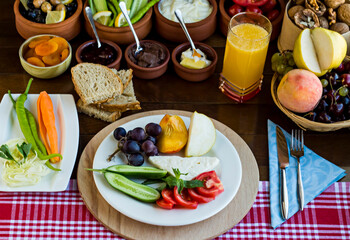 Meatless and Eggless Breakfast with fresh fruits,cheese,olives,dry fruits,fresh orange juice,whole wheat bread and fresh vegetables on the wooden table.