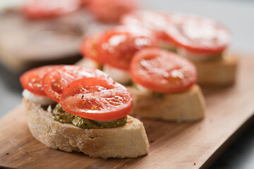 Bruschetta with tomatoes, mozzarella and pesto on olive wood board