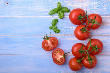 Fresh tomatoes with basil on blue background. Copy space, top view.