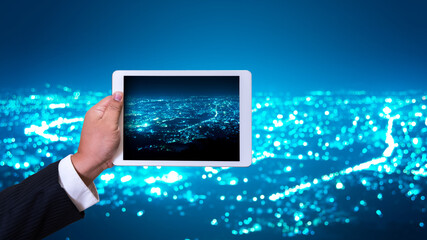 business man hand holding tablet on night cityscape view background