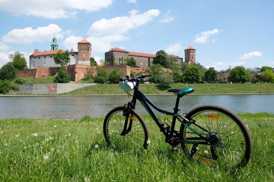 The bicycle stands on the grass by the Vistula River. In the background the Wawel Royal Castle. Cracow, Poland.
