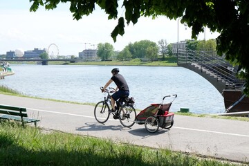 A man is ridding a bicycle with a trailer for child along the bike path along the Vistula River....