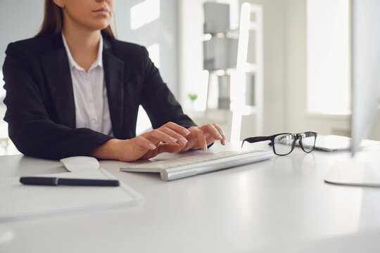 Work in the office at the computer. Business woman's handless face is typing on a computer keyboard.