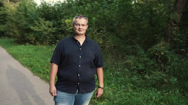 overweight guy looks at the camera against the background of the forest