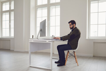 Businessman works at the computer at the table in the workplace in the office