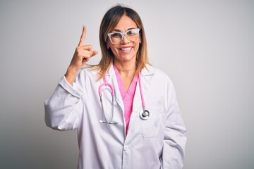 Middle age beautiful doctor woman wearing pink stethoscope over isolated white background pointing finger up with successful idea. Exited and happy. Number one.