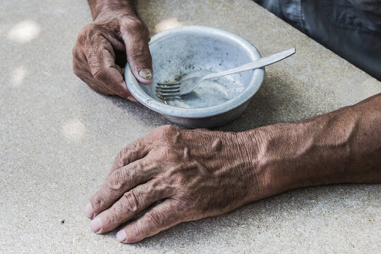 Hungry. Poor old man's hands an empty bowl. Selective focus. Poverty in retirement. Alms